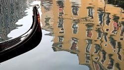 Uma gôndola é retratada enquanto prédios refletem na água, durante o carnaval de Veneza em 28 de janeiro de 2024. (Foto de GABRIEL BOUYS / AFP)