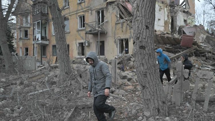 Moradores locais caminham entre os destroços de um edifício residencial parcialmente destruído por um ataque de mísseis na cidade de Selydove, região de Donetsk, em 8 de fevereiro de 2024, em meio à invasão russa da Ucrânia. (Foto de Genya SAVILOV/AFP)