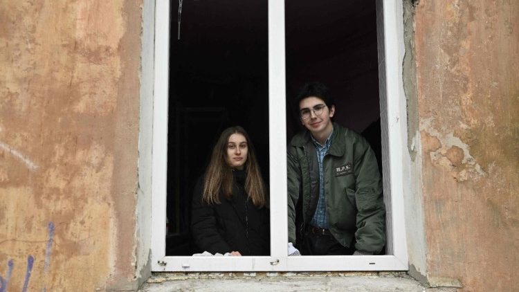 Sonya (L), 16, e Damir (R), 17, olham por uma janela quebrada enquanto posam para uma foto em um prédio residencial danificado por um ataque de mísseis na cidade de Selydove, região de Donetsk, em 8 de fevereiro. , 2024, em meio à invasão russa da Ucrânia. (Foto de Genya SAVILOV/AFP)
