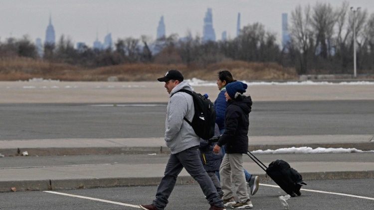 Des migrants récemment arrivés aux États-Unis se rendent à un arrêt de bus devant le refuge Flyod Bennett Field, le 21 février 2024, dans le quartier de Brooklyn à New York. 