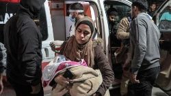 Eine Palästinenserin trägt ein Kind in eine Notaufnahme