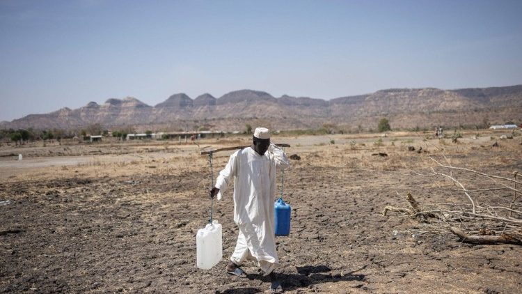 Ein sudanesischer Flüchtling, der in Äthiopien Zuflucht gefunden hat, kommt mit Wasser von einer Wasserstelle
