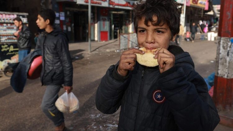 रफाह में एक बच्चा रोटी  खाते हुए