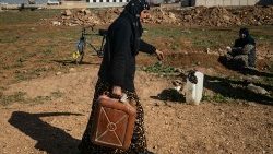 A woman carries gasoline in Qamishli, northeastern Syria