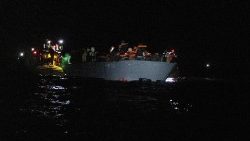 बचावकर्मी लीबिया के तट पर नाव पर सवार होकर बह रहे प्रवासियों की सहायता कर रहे हैं