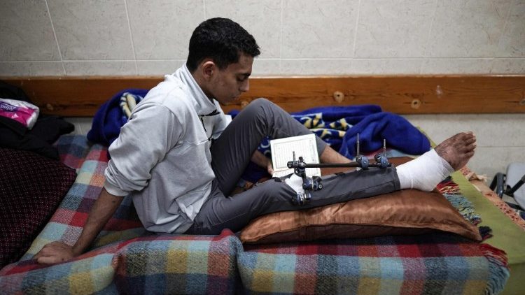 Un palestinese ferito, prega in un ospedale di Gaza (Afp)