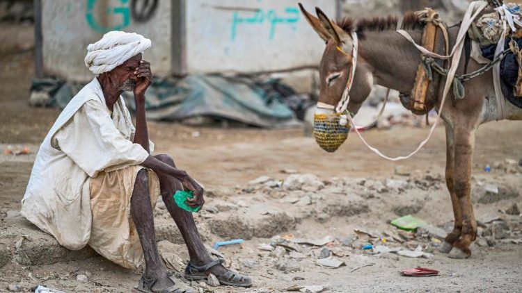 Un anziano sudanese aspetta di riempire la sua cisterna d'acqua trainata da un asino a Port Sudan