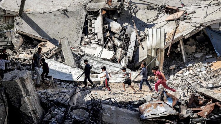 Crianças passam correndo pelos escombros de um prédio destruído em Rafah, no sul da Faixa de Gaza, em 9 de abril (AFP)
