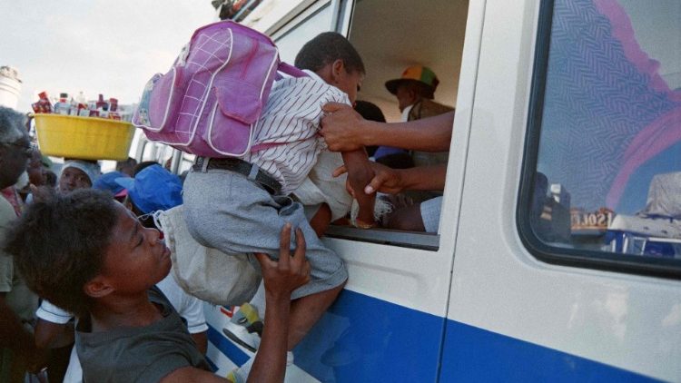 Eine Mutter hebt ihr Kind in einen Bus, der die Hauptstadt verlässt