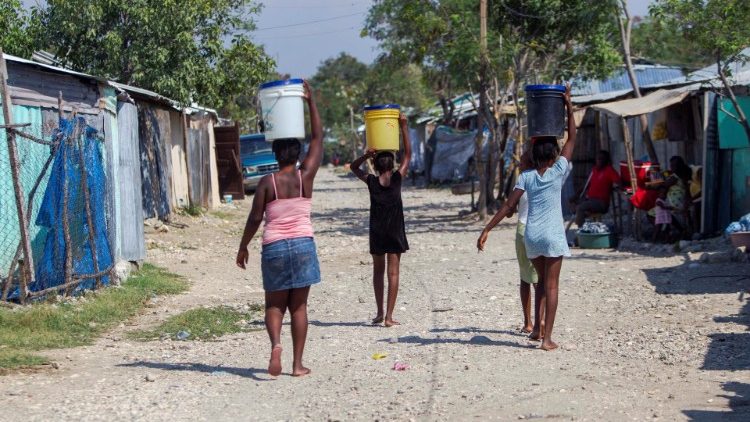 Women carry the water collected from La Piste camp in Port-au-Prince, Haiti