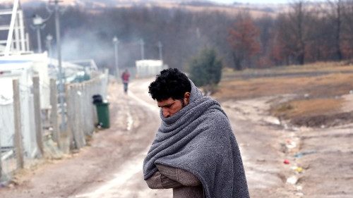 A migrant tries to warm himself at the Lipa camp in Bihac, Boznia and Herzegovina, 1 January 2021