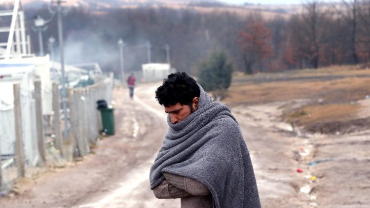 A migrant tries to warm himself at the Lipa camp in Bihac, Boznia and Herzegovina, 1 January 2021