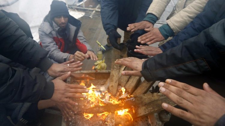Stranded migrants and refugees seek warmth around a small fire in Bosnia-Herzegovina