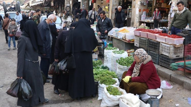 Syrians shop at a market in Damascus, as the nations marks 10 years of war