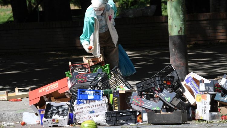 An elderly person searches for food among used food packages in Milan