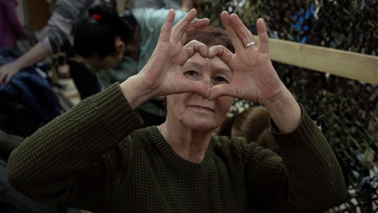 One of the women volunteers who prepare material for the defense of Ukraine, makes a heart with her hands, in Odessa, Ukraine