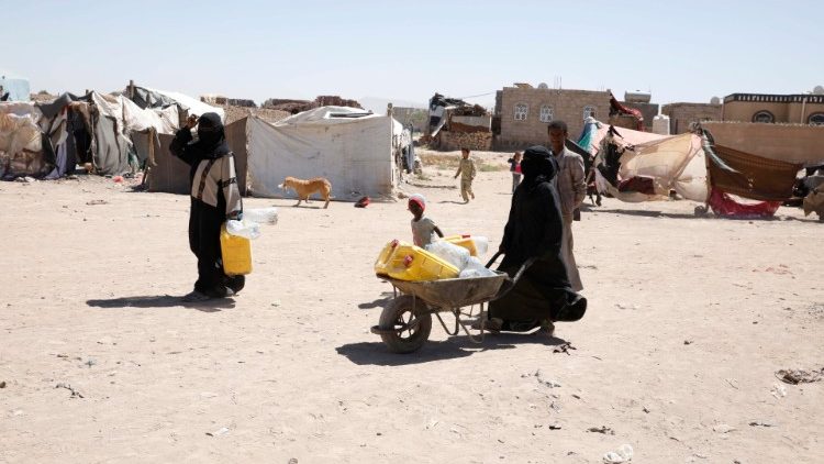 Yemenis walk through IDP camp on the outskirts of Sana'a