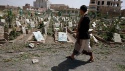 A man walks past portraits on the graves of war victims at a cemetery in Sana'a