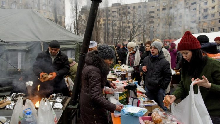 Lokalni mieszkańcy otrzymujący żywność w ramach zapomogi na placu pod budynkiem zniszczonym w ataku rakietowym, Dniepr, Ukraina, 15 stycznia 2023