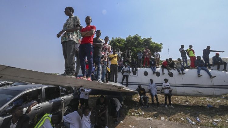 Menschen stehen auf einem alten Flugzeug, um der Messe am Flughafen von N'Dolo besser folgen zu können