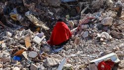 A woman sits on the rubble of her home where the bodies of her family members are still buried, in Hatay, Turkey