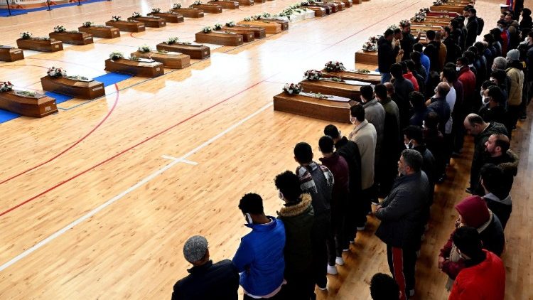 People pray near the caskets of deceased migrants in Crotone