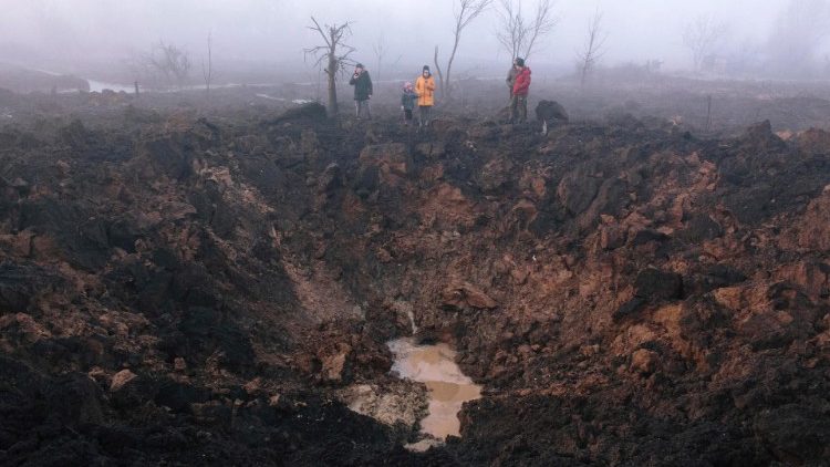 Moradores se reúnem em torno de uma cratera de bombardeio depois que um foguete atingiu o bairro de Pisochyn, nos arredores de Kharkiv, Ucrânia, em 09 de março de 2023. EPA/PAVLO PAKHOMENKO