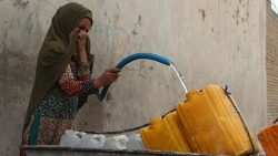 An Afghan woman fills up jerry cans with drinking water in Kandahar