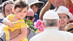 Mãe segura sua filha que oferece flores ao Papa Francisco na Audiência Geral de 28/06/2023