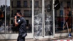 A police officer walks past a broken window caused by riots in Nanterre