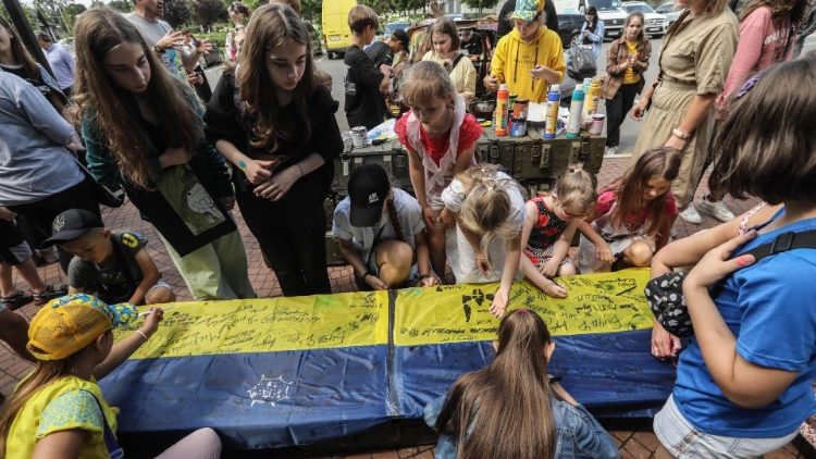 Artyści i dzieci podpisują ukraińską flagę w Buczy, 30 czerwca 2023