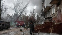 An elderly woman in Donetsk walks past a building damaged by shelling