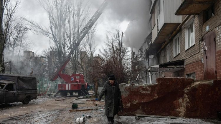 An elderly woman in Donetsk walks past a building damaged by shelling