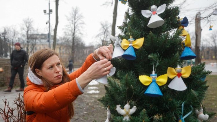 यूक्रेन में क्रिसमस ट्री सजाती एक महिला
