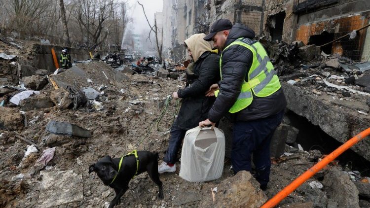 Um policial ajuda um homem local com um cachorro a evacuar o local de um prédio danificado após um ataque com mísseis em Kiev, Ucrânia, 2 de janeiro de 2024. EPA/SERGEY DOLZHENKO