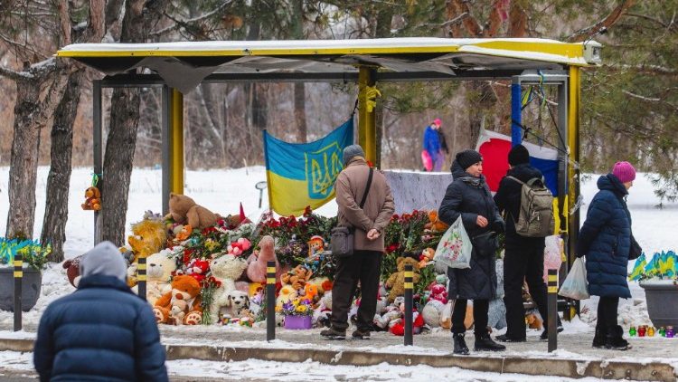 Ucranianos levam homenagens e flores em um ponto de ônibus perto das ruínas de um prédio residencial destruído por um ataque com mísseis em 14 de janeiro de 2023, em Dnipro, sudeste da Ucrânia, em 14 de janeiro de 2024.. EPA/ARSEN DZODZAIEV