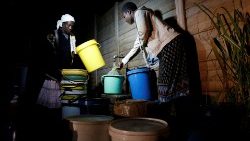 Des femmes viennent chercher de l'eau dans la nuit et pendant une coupure de courant, dans une banlieue de Harare, le 30 juin 2019