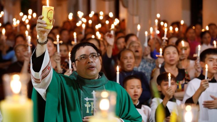 Catholic priest Anthony Dang Huu Nam holds a candle during a mass prayer for 39 people found dead in the back of a truck near London, UK at My Khanh parish in Nghe An province