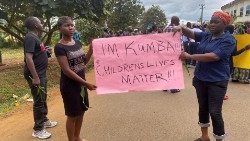 People hold a banner in protest after the murder of school children in Kumba