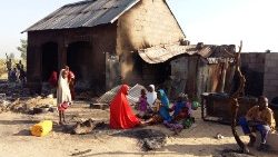 Menschen sitzen in der Nähe eines niedergebrannten Hauses nach einem Angriff von mutmaßlichen Mitgliedern der islamistischen Boko Haram-Rebellen im Dorf Bulabulin