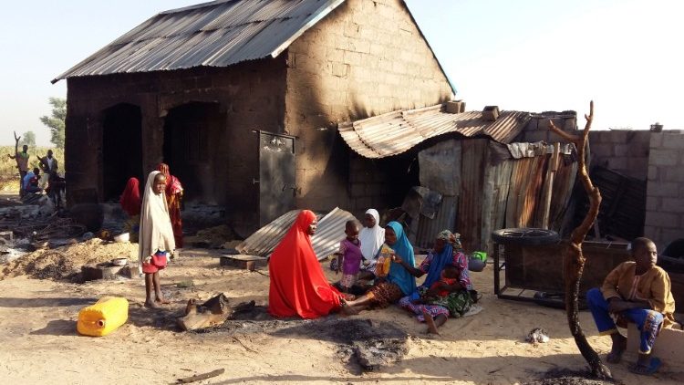Nigeryjska rodzina przy spalonym przez islamistów domu