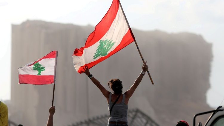 Demonstrators wave Lebanese flags during protests near the site of a blast at Beirut's port area