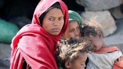 Mulher iemenita com seus filhos aguarda o fornecimento de alimentos pelas organizações humanitárias