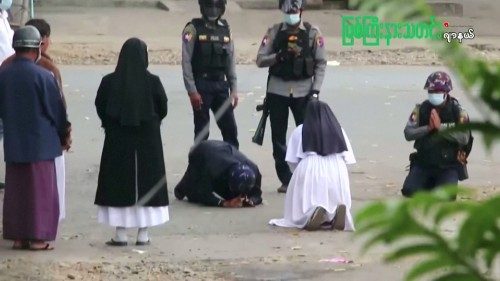 Myanmar nun Sister Ann Rose Nu Tawng kneels in front of police officers.