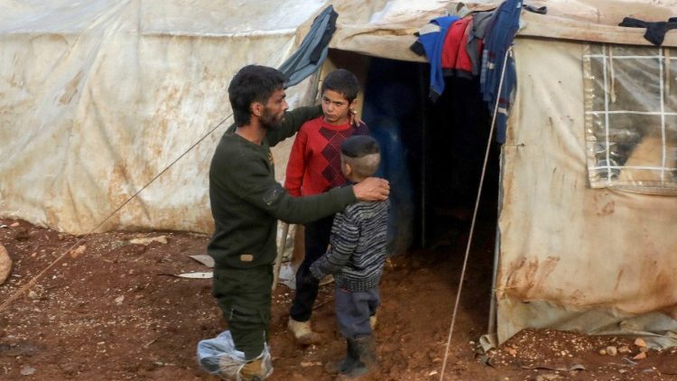 Ahmad Hamra, es fotografiado con sus hijos fuera de una tienda de campaña en un campamento de desplazados internos sirios, en el norte de Alepo, cerca de la frontera sirio-turca, Siria 17 de febrero de 2021.