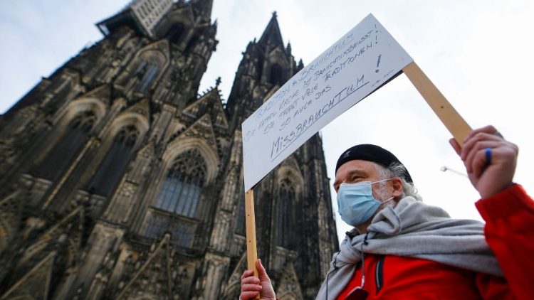 Demonstrant mit Plakat zur Aufarbeitung von Missbrauchsällen vor dem Kölner Dom