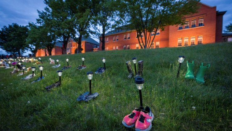 Pairs of children's shoes and toys are seen at memorial in front of the former Kamloops Indian Residential School