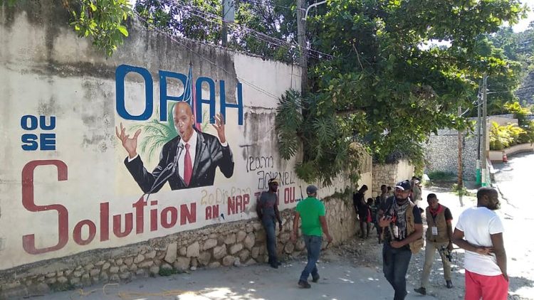 Người dân đi qua bức tường vẽ hình tổng thống Moise sau khi ông bị ám sát.