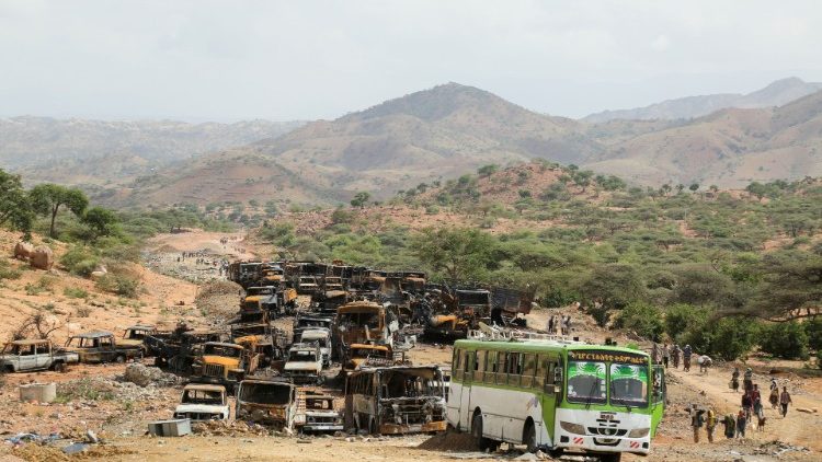 Villagers walk past burnt vehicles, a grim aftermath of the Tigray conflict