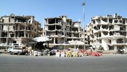 Vegetables are displayed for sale near damaged buildings in Homs, Syria